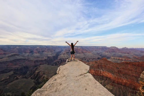 A girl looks at the Grand Canyon with admiration and her hands raised up